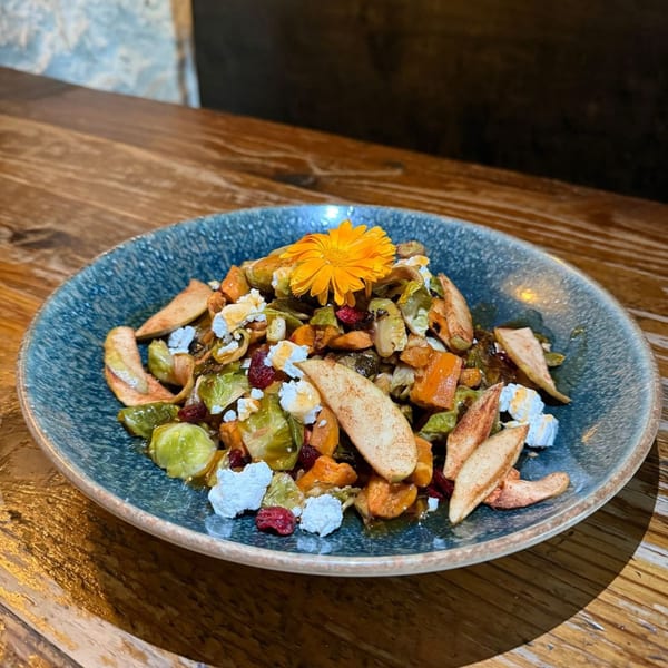 A colorful salad with brussels sprouts, butternut squash, apples, cranberries, and feta cheese.